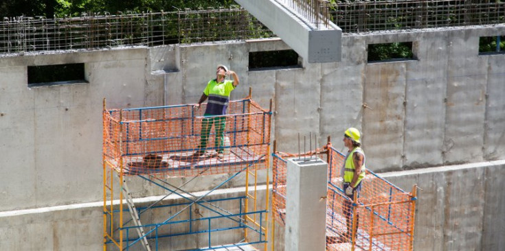 Dos treballadors de la construcció treballen en una obra d’un dipòsit d’aigua.