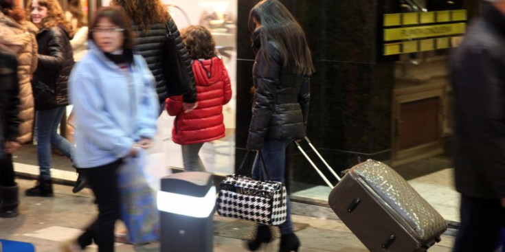Una turista amb la seva maleta a l’eix comercial de la capital.