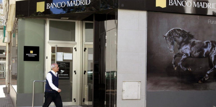 Un home passa davant d'una oficina tancada de Banco Madrid.