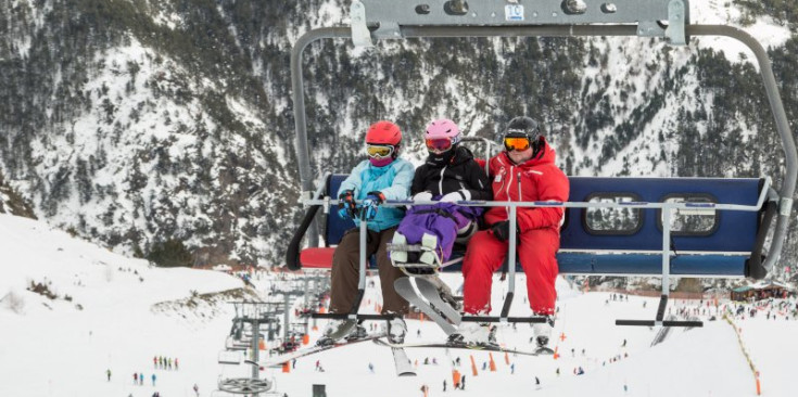 Tres esquiadors utilitzen un telecabina de les pistes del país.