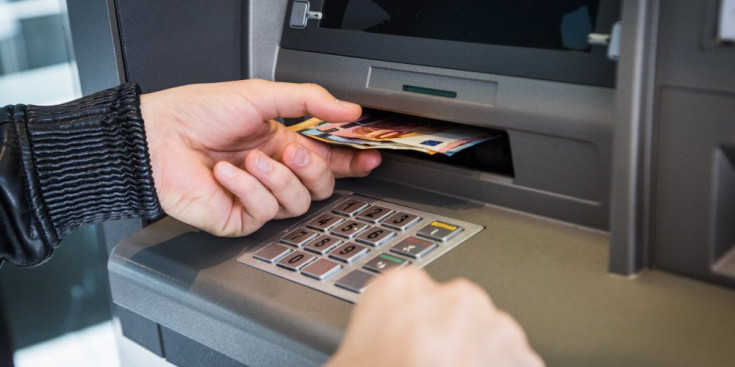 Una clienta d’una entitat bancària treu diversos bitllets des d’un caixer automàtic.
