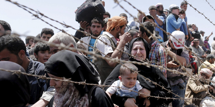 Refugiats sirians esperen creuar des del seu país la frontera que els separa de Turquia.