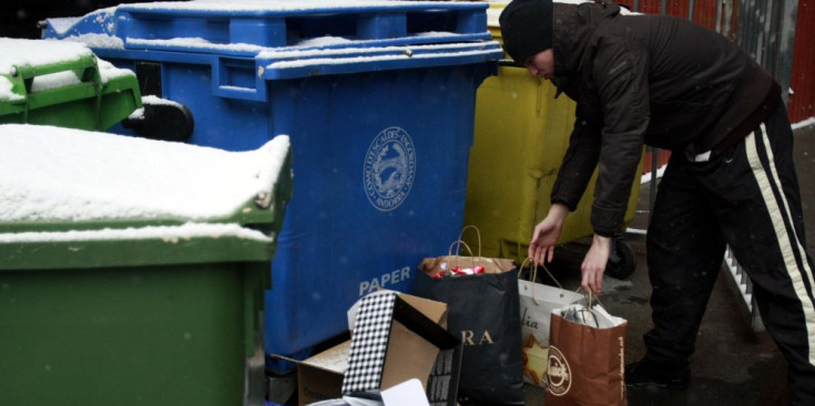 Un home deixa unes bosses al costat dels contenidors d’escombraries.