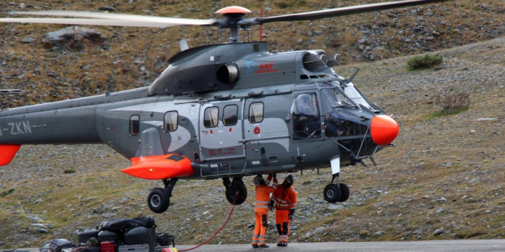 Els operaris encarregats d'instal·lar les pilones preparen l'helicòpter per a les maniobres.