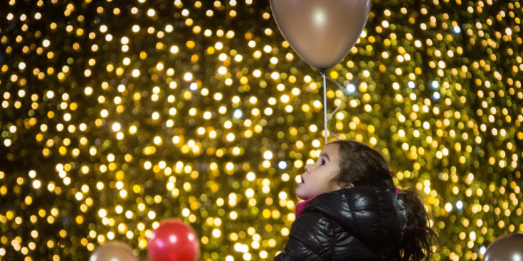 Una nena contempla bocabadada l’arbre de Nadal ubicat a la plaça Coprínceps, ahir.