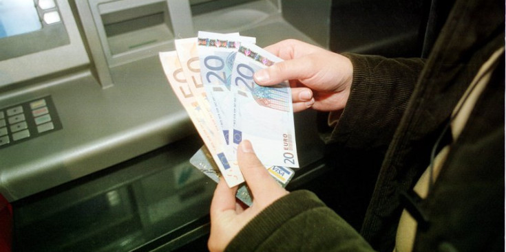 Un ciutadà subjecta diners després de fer un reintegrament a través del caixer automàtic.