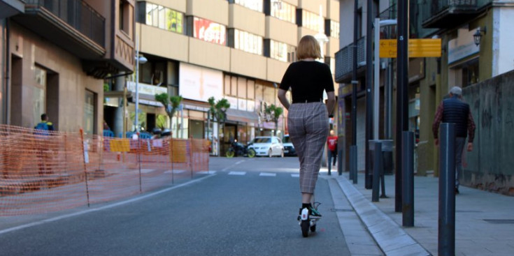 Una noia circula amb patinet per un carrer d’Andorra la Vella.