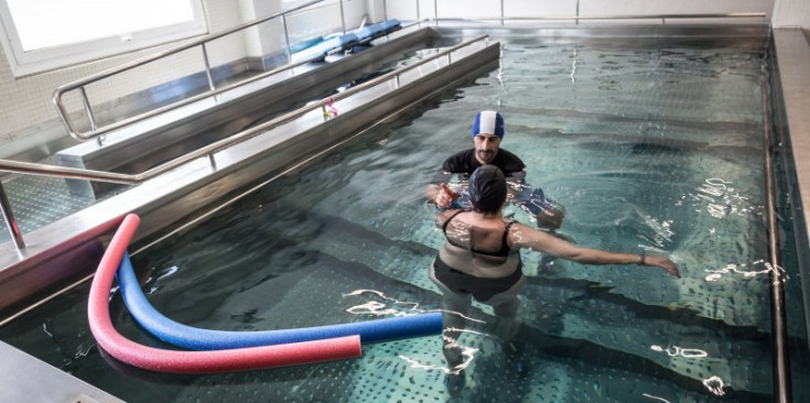 Una pacient i el seu fisioterapeuta a la piscina de rehabilitació de l’hospital.