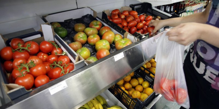 Un consumidor utilitza una bossa de plàstic a la secció de fruites i verdures.