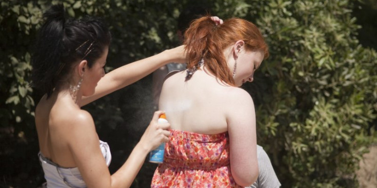 Una dona posa crema solar a l’esquena d’una altra.