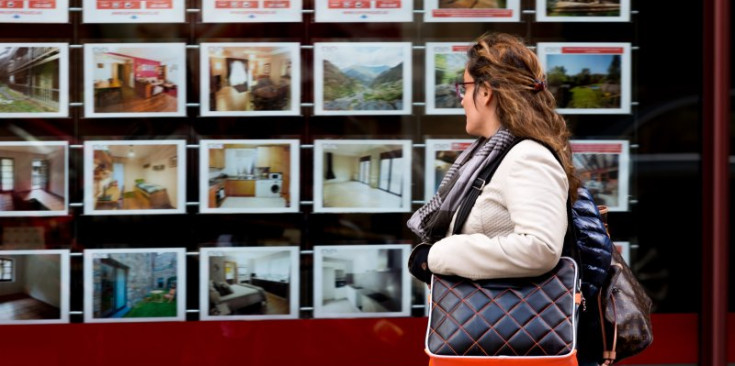 Una dona observa l’oferta d’habitatges a l’aparador d’una immobiliària.