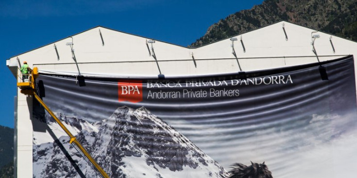 Un operari despenja un dels cartells que publicitava Banca Privada d’Andorra, que penjava d’un edifici d’Andorra la Vella.