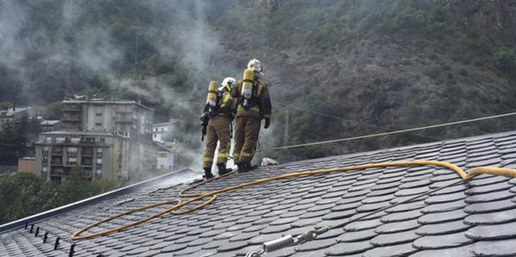 Dos bombers apagant el foc de la teulada de l'Hotel Glòria.