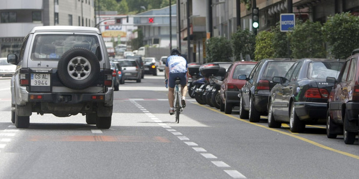 Un ciclista circula per una calçada sense carril senyalitzat per a bicicletes.