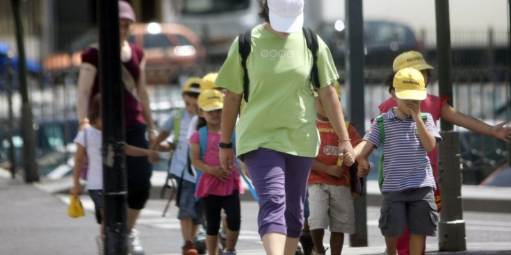 Una monitora passeja pels carrers d’Andorra amb els nens del casal.