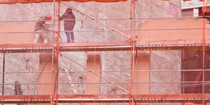Uns obrers treballen en la façana d'un edifici.