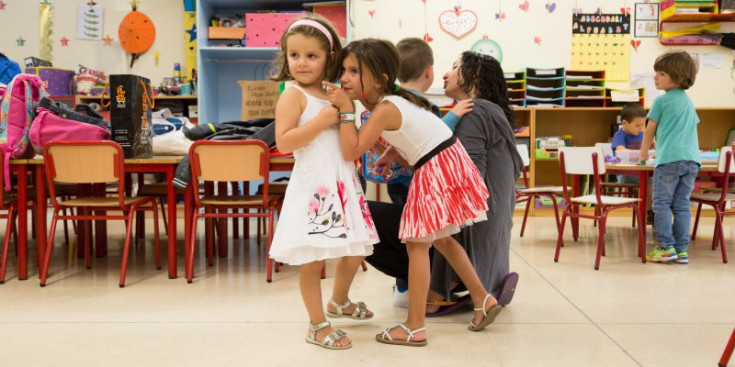 Dues nenes es retroben a l’aula el primer dia de curs després de les vacances d’estiu, ahir.