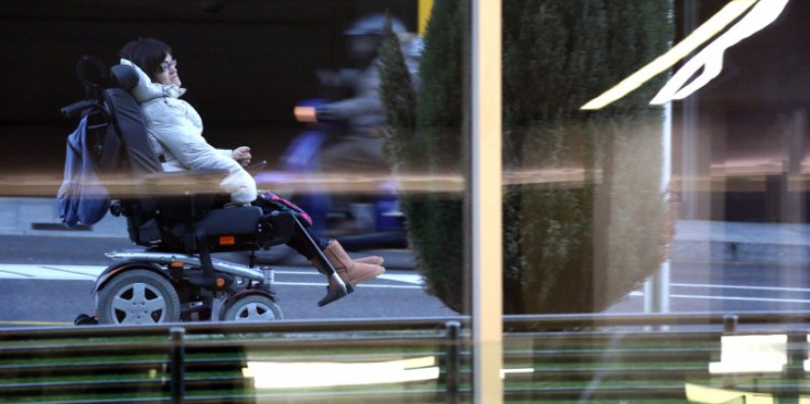 Una dona en cadira de rodes passeja per la capital.